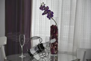 a vase with purple flowers on a glass table with glasses at Apartament Mihaela in Mamaia