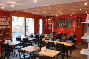 un restaurante con mesas y sillas de madera y paredes rojas en Le Café-Hôtel de L'Aubier en Neuchâtel