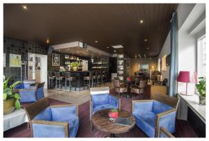 a restaurant with blue chairs and a table and a bar at Hotel Ter Streep in Ostend