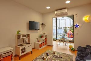 a living room with a playroom with a table and a tv at H4 Hotel Arcadia Locarno in Locarno