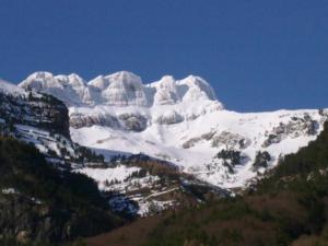 a mountain covered in snow with trees in front of it at Casa Marieta in Canfranc-Estación