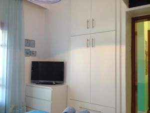 a living room with white cabinets and a tv at Garden Summer House in Nea Kallikrateia
