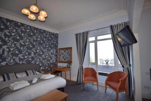 um quarto com uma cama, uma televisão e uma janela em The Babbacombe Hotel em Torquay