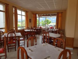 un comedor con mesas, sillas y ventanas en Hostal Orly, en Camponaraya