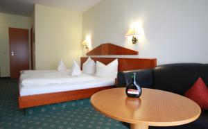 una habitación de hotel con una cama y una botella de vino en una mesa en Weinhotel Rose, en Volkach