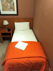 Cama en habitación con manta naranja en Hotel UTHGRA de las Luces en Buenos Aires