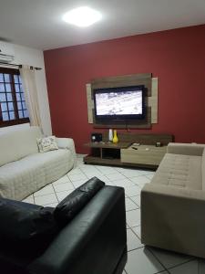 a living room with a couch and a flat screen tv at Casa em Ponta Negra in Natal
