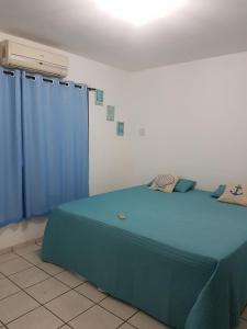 a bedroom with a bed with blue curtains and a heater at Casa em Ponta Negra in Natal
