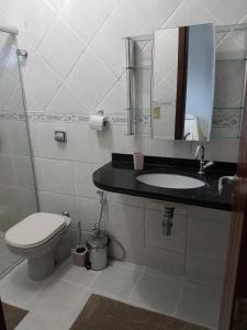 a bathroom with a toilet and a sink and a mirror at Casa em Ponta Negra in Natal