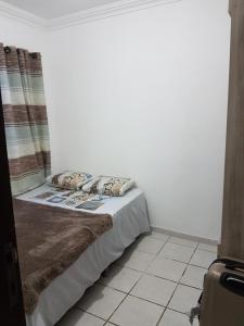 a bed in a room with a white wall at Casa em Ponta Negra in Natal