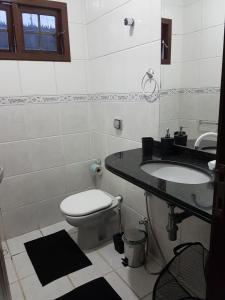 a white bathroom with a toilet and a sink at Casa em Ponta Negra in Natal