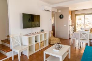 een woonkamer met witte meubels en een tv aan de muur bij Empordà Residencial in L'Estartit