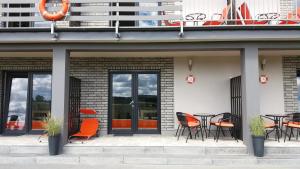 a patio with orange chairs and tables on a building at Amber Jarosławiec in Jarosławiec