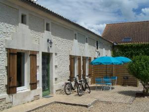 deux vélos garés à côté d'un immeuble avec des parasols bleus dans l'établissement Chez Jousseaume Chambre d'Hôtes et Gites, à Saint-Ciers-Champagne