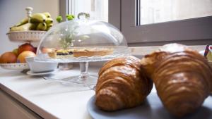two croissants and a cake in a glass dome on a counter at Suite Inn Rome in Rome