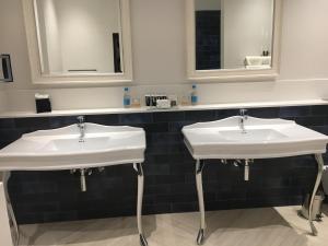 two sinks in a bathroom with two mirrors at Lainston House in Winchester