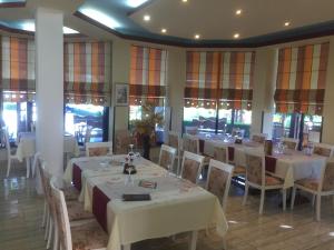 un restaurante con mesas y sillas blancas y ventanas en Aragosta Shengjin en Sakës