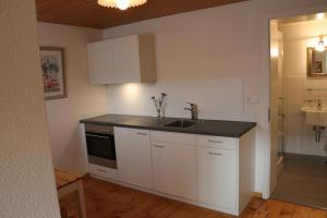 a kitchen with white cabinets and a sink at Hotel Lowen in Walenstadt