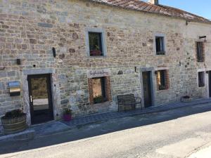 un edificio de piedra con dos puertas y un banco al aire libre en Le gîte du faubourg, en Sautour