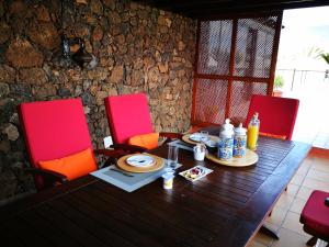 una mesa de madera con dos sillas rojas alrededor en Villa la petite en Guatiza