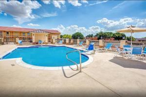 a large swimming pool with chairs and umbrellas at Arya Inn & Suites in Farmers Branch