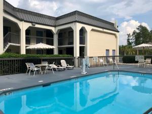 une piscine avec des chaises et des tables en face d'un hôtel dans l'établissement Days Inn by Wyndham Walterboro, à Walterboro