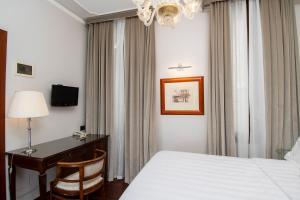 ヴェネツィアにあるホテル カーサ ヴァラルド レシデンツァ デポカのベッド、デスク、シャンデリアが備わるホテルルームです。
