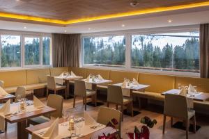 ein Restaurant mit Tischen und Stühlen und großen Fenstern in der Unterkunft Hotel Sonnalpen in Damüls