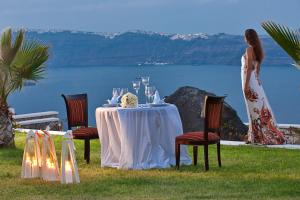 a woman standing next to a table with wine glasses at Maison Des Lys - Luxury Suites in Akrotiri