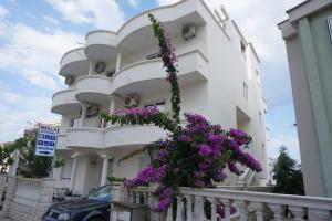 ein weißes Gebäude mit lila Blumen darauf in der Unterkunft Molla Apartments in Ulcinj