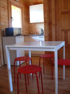 a kitchen with a white table and two red stools at Anielsko domki nad morzem in Mielenko