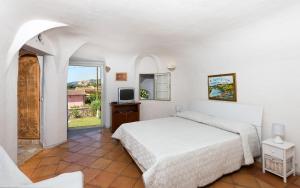 ein weißes Schlafzimmer mit einem Bett und einem TV in der Unterkunft EMME B&B in Arzachena