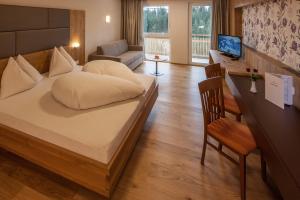 Schlafzimmer mit einem Bett, einem Schreibtisch und einem Stuhl in der Unterkunft Hotel Sonnalpen in Damüls