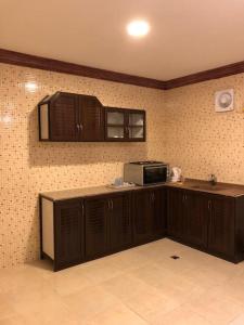 a kitchen with wooden cabinets and a microwave at شقق بيوت الشرق المخدومة-اقتصادي in Al Khobar +13 photos