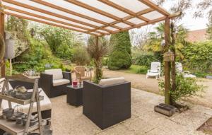 un patio con pérgola, mesa y sillas en le jardin de Camille en Tailleville