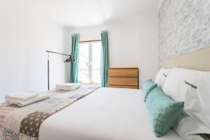 - une chambre blanche avec un grand lit et une fenêtre dans l'établissement Casas do Beco Charming Flats, à Lisbonne