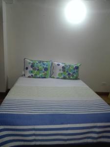 a bed with blue and white striped sheets and pillows at Family Haclams in Zipaquirá