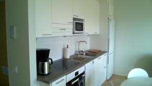 a white kitchen with a sink and a microwave at Lutakko Apartment with free car parking in Jyväskylä