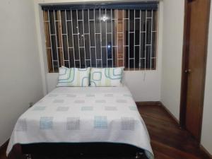 a bed in a small room with a window at Family Haclams in Zipaquirá