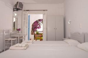 a white bedroom with two beds and a desk at Nikoleta's Studios in Drios