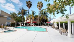 a swimming pool with tables and chairs and palm trees at Chase Suite Hotel Newark Fremont in Newark