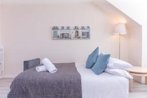 um quarto branco com uma cama com almofadas azuis em Ailsa Retreat em Troon