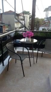 a table and chairs with a vase of flowers on a balcony at Apartment by the Beach in Neoi Epivates