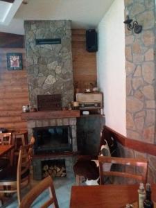 Una habitación con chimenea de piedra con mesa y sillas. en Mountain house Campari, en Mavrovo