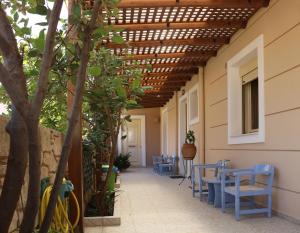 a patio with blue chairs and a wooden pergola at Helianthus in Agia Pelagia