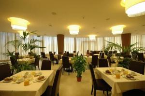 un restaurante con mesas blancas, sillas y plantas en Mediterraneo Palace Hotel, en Amantea