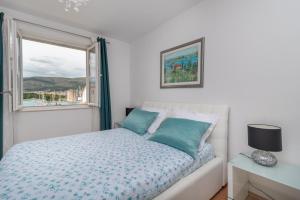 ein weißes Schlafzimmer mit einem Bett und einem Fenster in der Unterkunft Apartments Maria in Trogir
