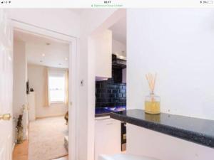 una cucina con pareti bianche e piano di lavoro nero di Cosy Studio Apartment In FULHAM a Londra