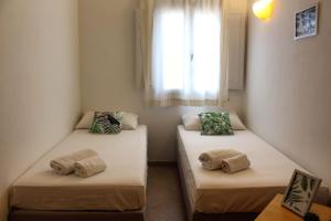 two twin beds in a room with a window at Exclusive Marina Apartment in Castellammare del Golfo