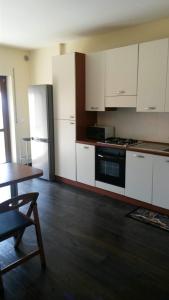 a kitchen with white cabinets and a table and a refrigerator at Appartamento Via Gentile in Foggia